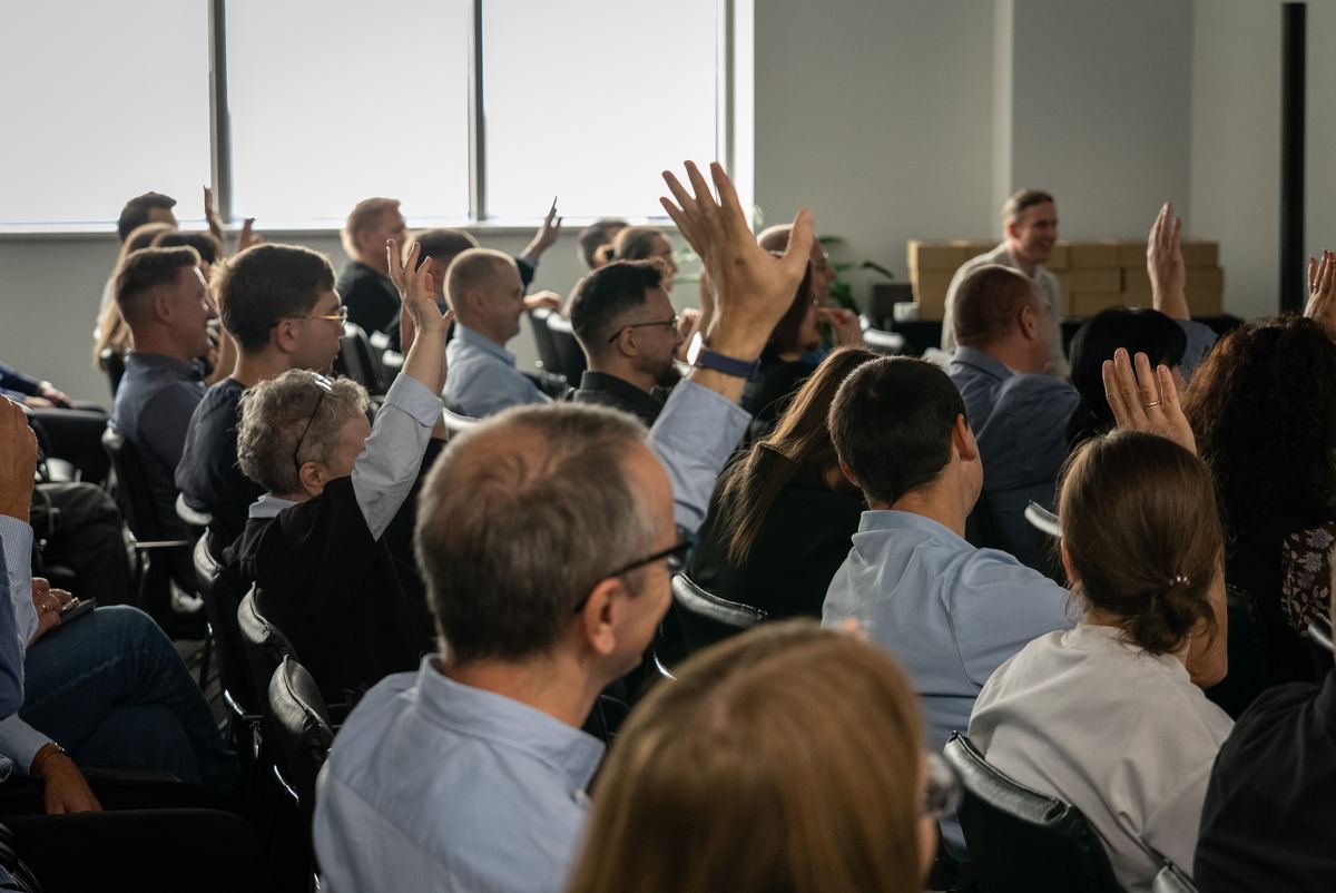 Uczestnicy konferencji podnoszą ręce na sali